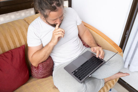 Freelancer working from home sitting on sofa using laptopの写真素材