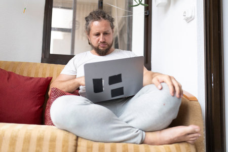 Freelancer working from home on laptop in comfortable clothesの写真素材