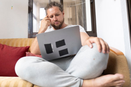 Freelancer concentrating and working from home using laptop on sofaの写真素材