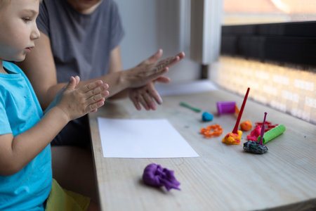 Toddler and teacher clapping hands before playing with modeling clayの写真素材