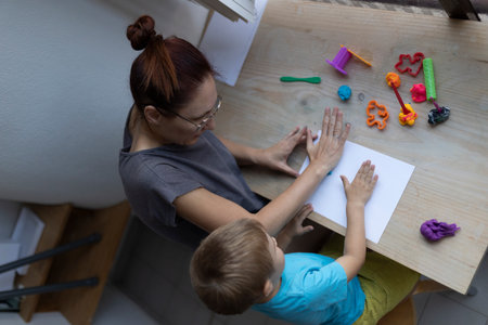 Teacher helping child playing with modeling clay in art classの写真素材