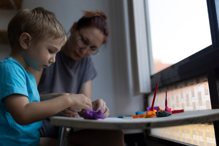 Child and art teacher sculpting with colorful clay in art classの写真素材