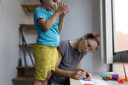 Mother and child creating art with modeling clay at homeの写真素材