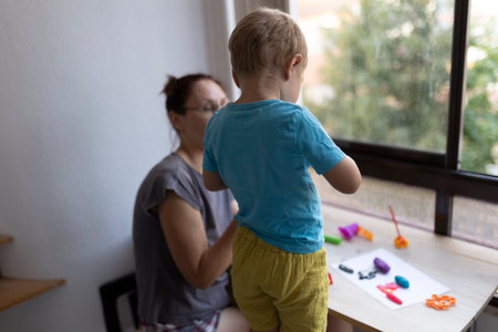 Toddler playing with modeling clay at home with parent supervisingの写真素材