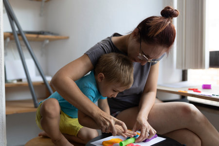 Mother and son creating colorful clay art at homeの写真素材