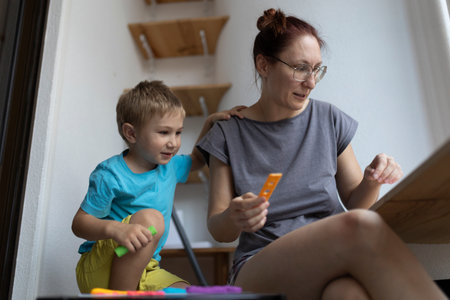 Mother and son engaging in creative play with colorful clay at homeの写真素材