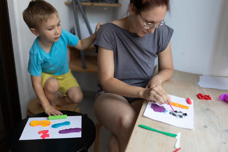 Mother and son creating colorful artwork with modeling clay at homeの写真素材