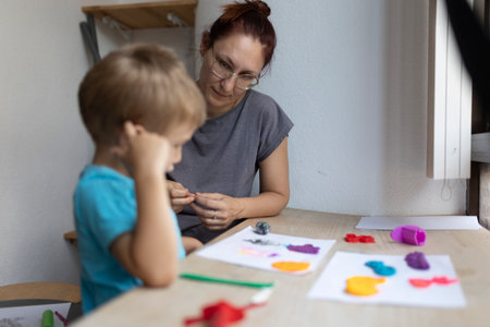 Teacher helping child with modeling clay in art classの写真素材