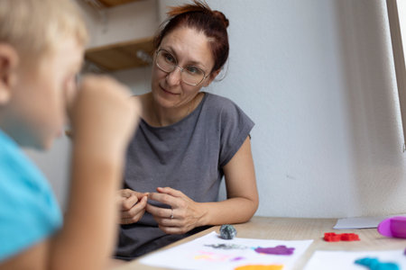 Art teacher helping child sculpting with clay in art classの写真素材