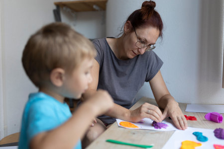 Mother and son creating colorful artwork with modeling clay at homeの写真素材
