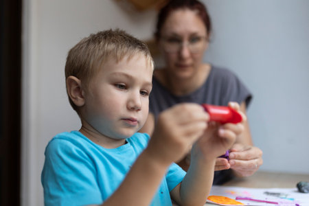 Child playing with modeling clay with teacher supervisingの写真素材