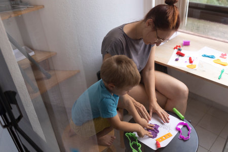 Mother and son creating colorful clay art at homeの写真素材