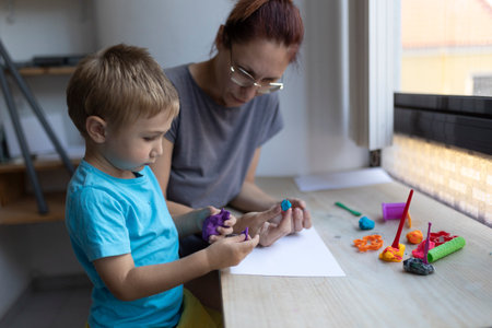 Mother and child playing with modeling clay at homeの写真素材