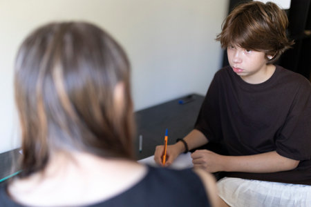 Teenage boy writing notes during therapy session with counselor