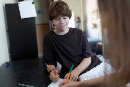 Boy and girl drawing together at home: homeschooling and creative activities