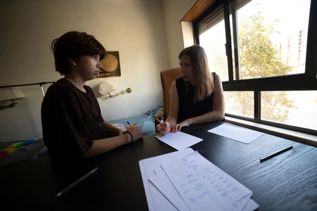 Private tutor helping teenage student with homework in bedroom