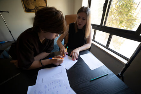 Private tutor helping young student with homework indoors