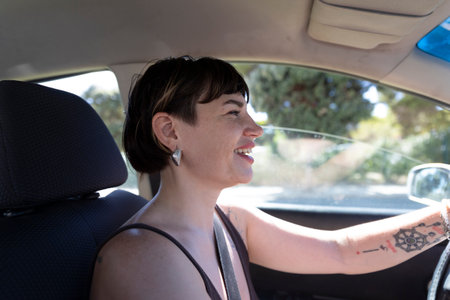 Young woman driving car and smiling during summer dayの写真素材
