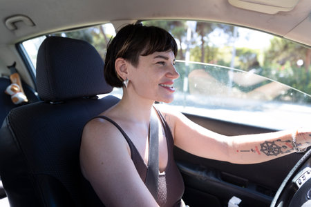 Young woman driving car smiling and looking away