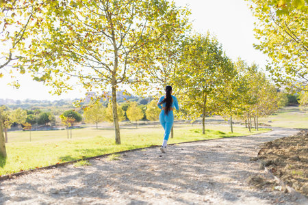 Sportswoman jogging in a park during a sunny autumn dayの写真素材