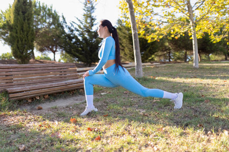 Young sportswoman stretching legs in a park before runningの写真素材