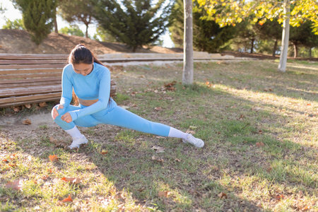 Young sportswoman stretching legs in a parkの写真素材
