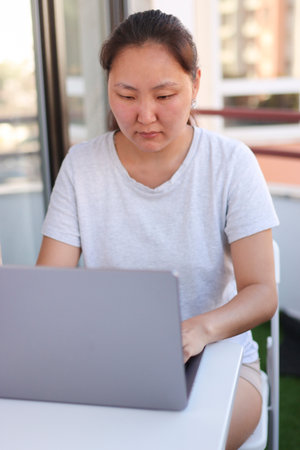 Asian freelancer woman working on laptop on balcony at homeの写真素材