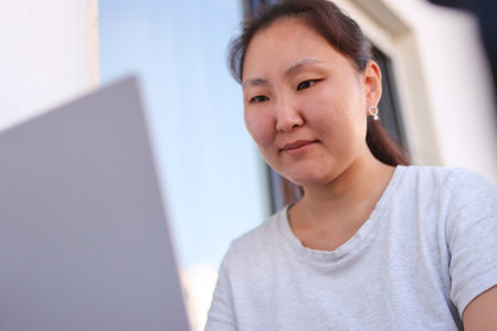 Asian freelancer woman working on laptop at home office balconyの写真素材