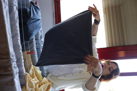 Woman hanging laundry on clothesline indoorsの写真素材