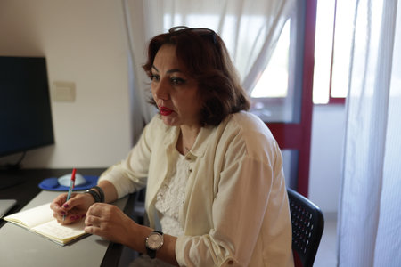 Businesswoman working from home taking notes and following online meetingの写真素材