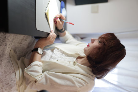 Businesswoman writing notes in notebook at office deskの写真素材