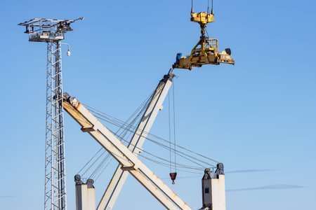Industrial crane transfers the yellow cargo from one place to anotherの写真素材