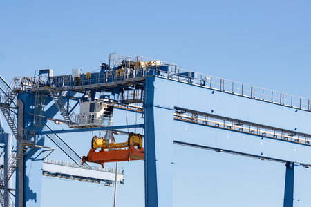 Large lifting structures with suspended spreader for cargo containers on the background of the blue skyの写真素材
