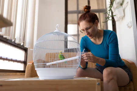 Woman changing water in bird cage at homeの写真素材