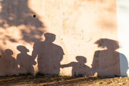 Family silhouette projected on wall during golden hourの写真素材