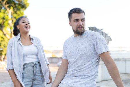 Cheerful young woman laughing with pensive young man outdoorsの写真素材