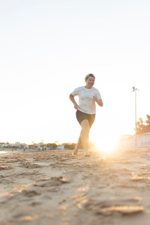 Woman running barefoot on the beach at sunset