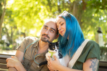 Young couple holding a kitten are enjoying a sunny day in the parkの写真素材