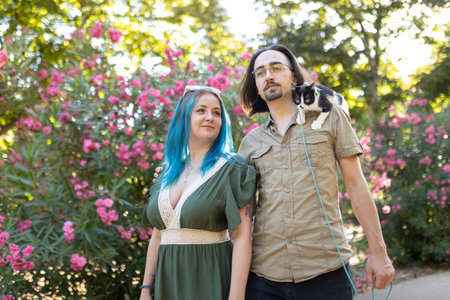 Young couple walking with cat on leash in park