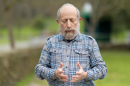 Senior man meditating in public park, finding inner peace and mindfulness