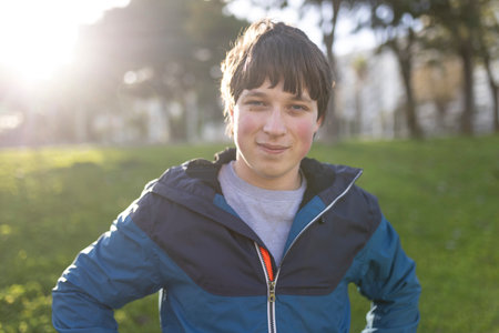 Portrait of smiling teenager posing in park during golden hour