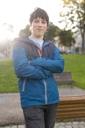 Confident teenager posing with crossed arms in park