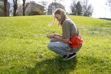 Young woman picking flowers in a public park on a sunny dayの写真素材