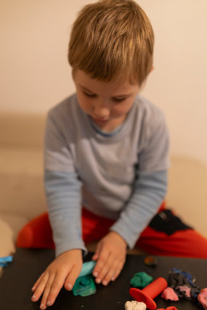 Child playing with modeling clay at home: developing creativity and fine motor skills