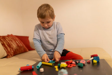 Child playing with modeling clay on a table at home