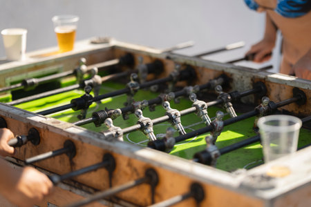 Friends playing foosball outdoors, enjoying drinks and summer fun