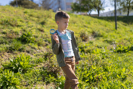 Curious child exploring nature with magnifying glass in park