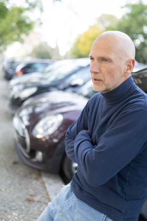 Senior man waiting with folded arms near parked carsの写真素材