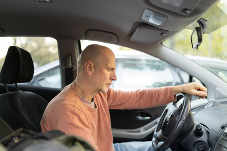 Senior man driving car and looking out window contemplating life journey