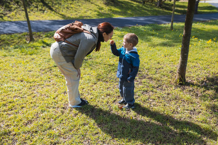 Mother and son smelling a flower in the park during springtime